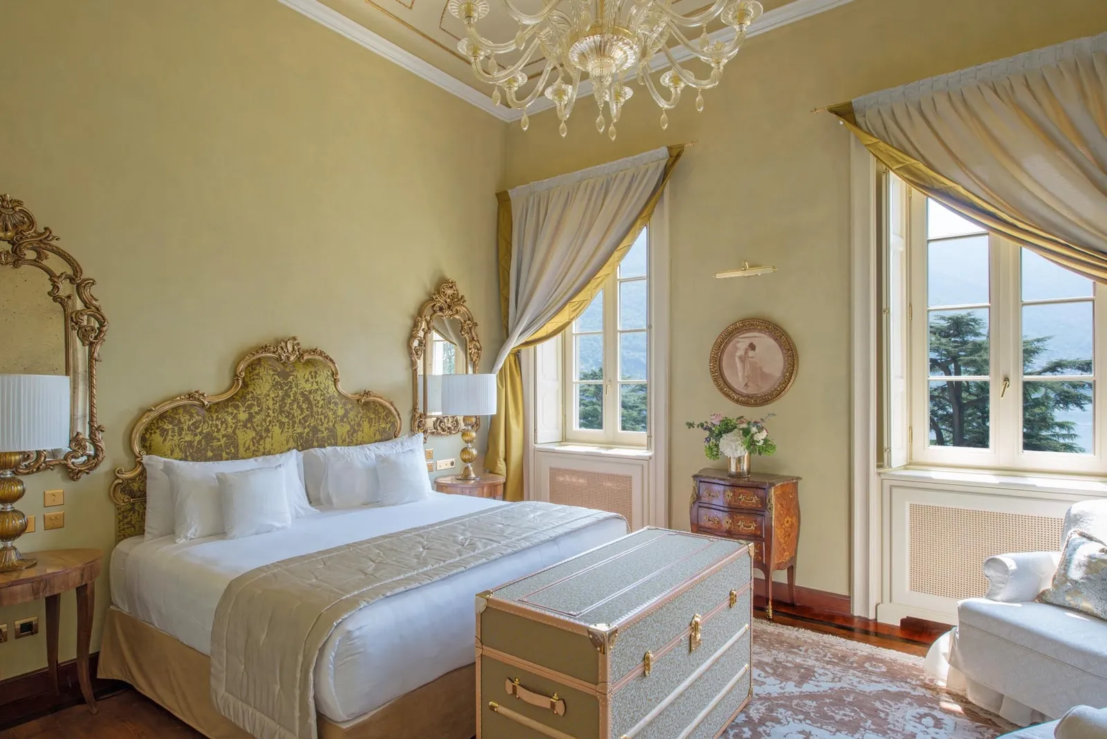 Room in the Villa with Lake View, a gilt headboard and pale curtains