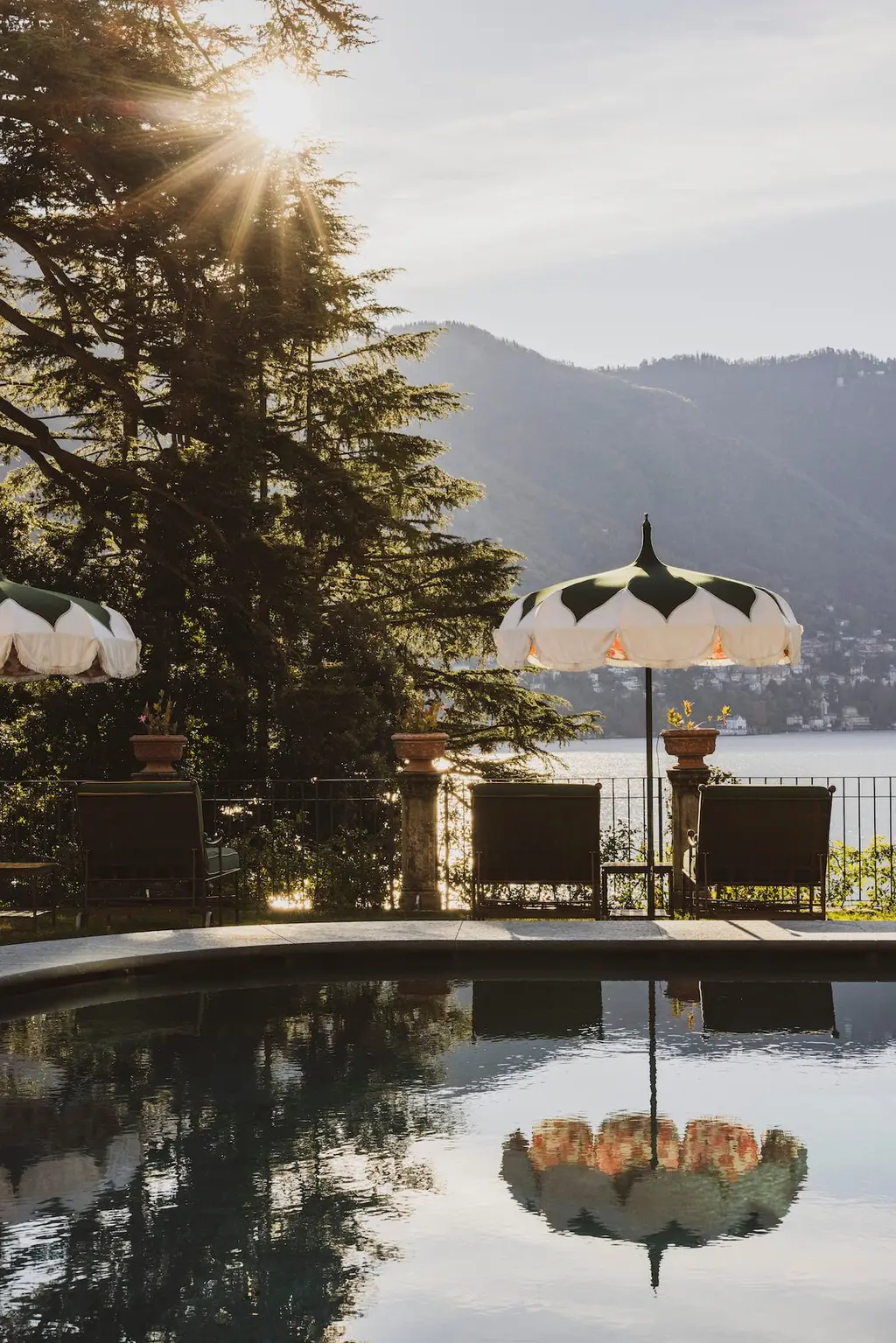 A parasol by a pool at sunset, with the lake beyond