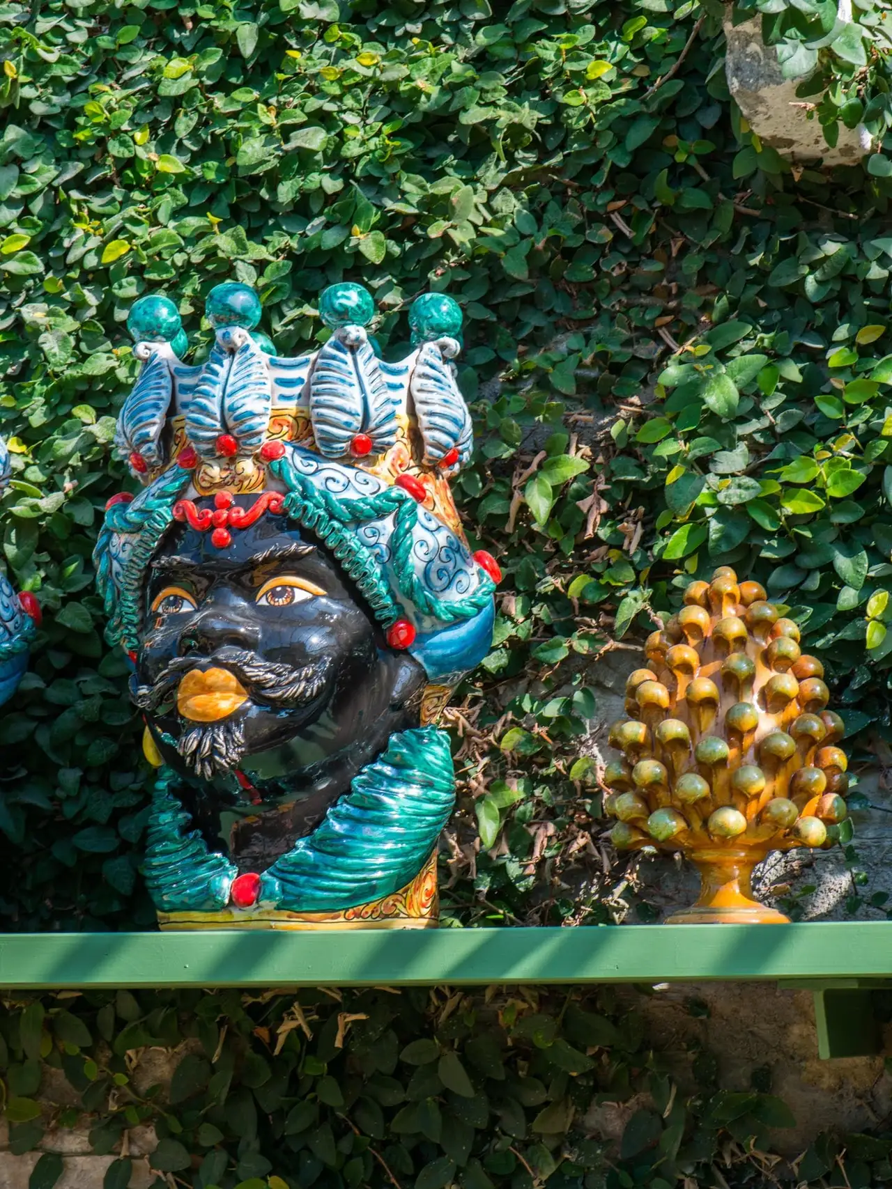 A ceramic head and pine-cone vases in the Winter Garden by the pool