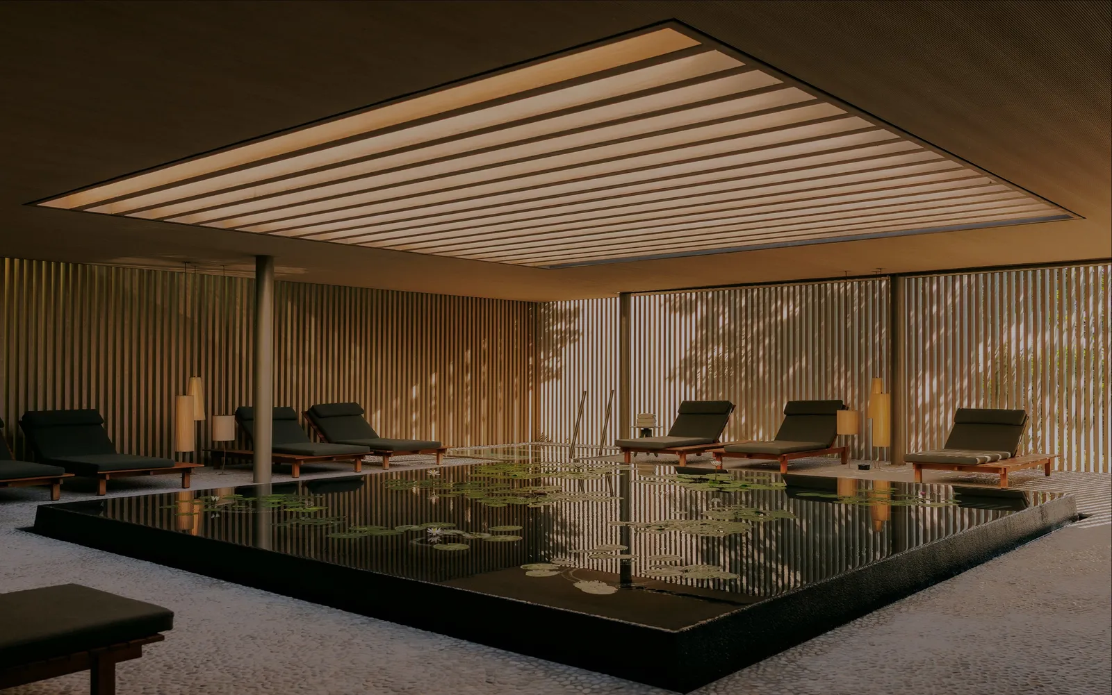 The dark pool of the FLOW spa under its slatted ceiling, loungers along the glass