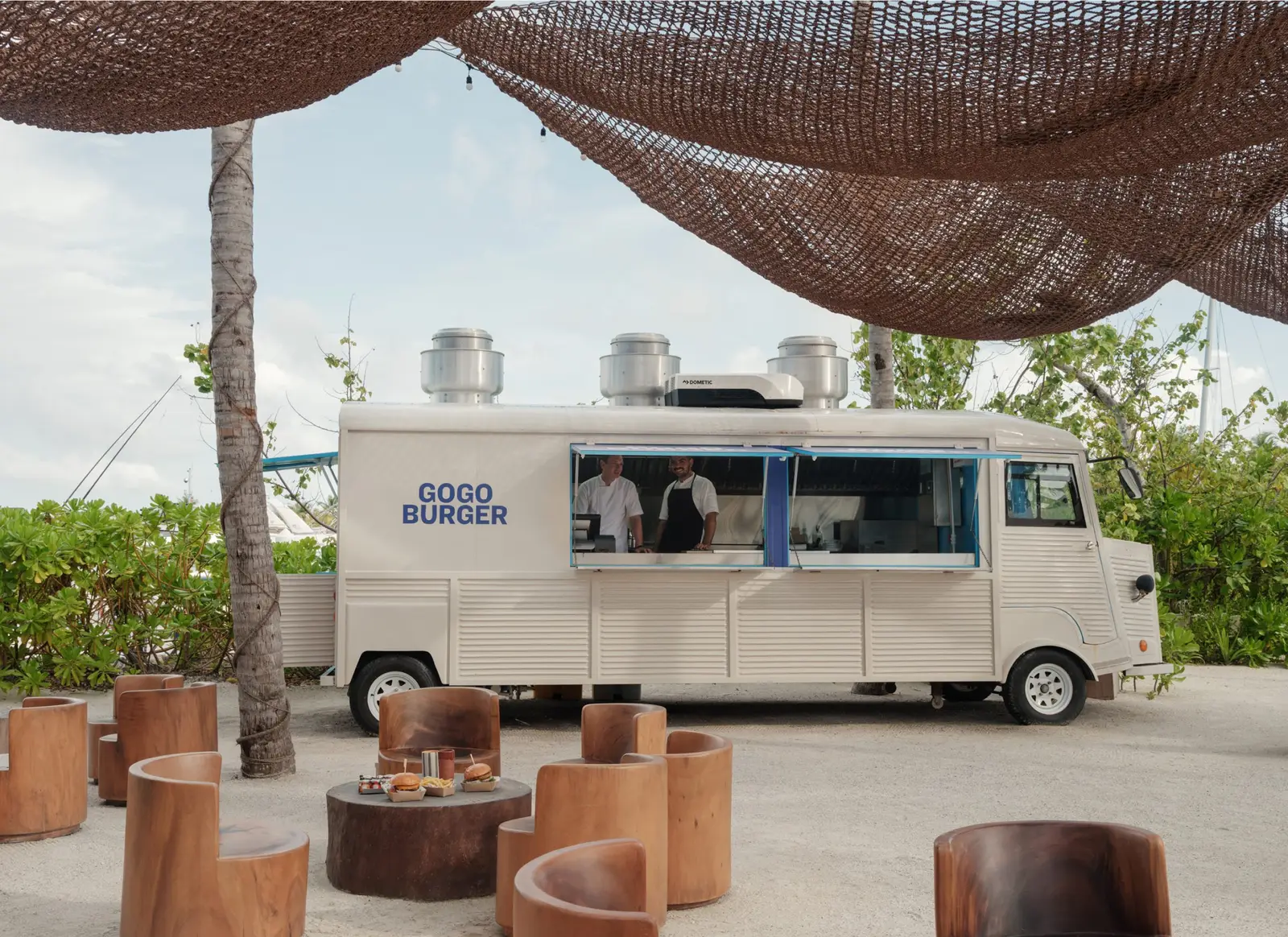The Go Go Burger van under the palms, wooden tables on the sand
