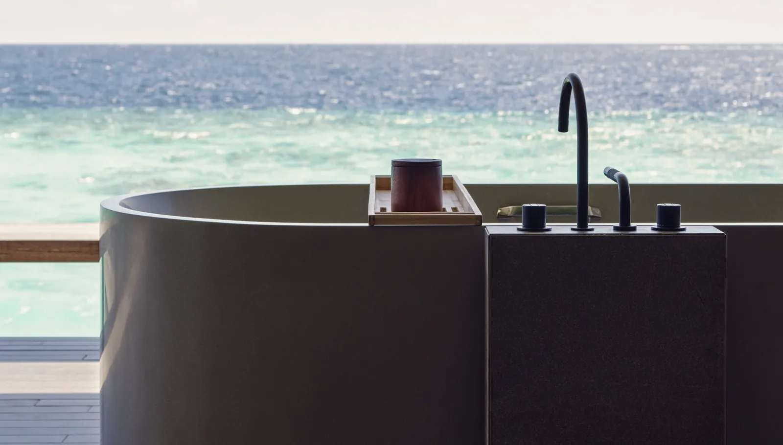 A dark bathtub on the deck, facing the open sea