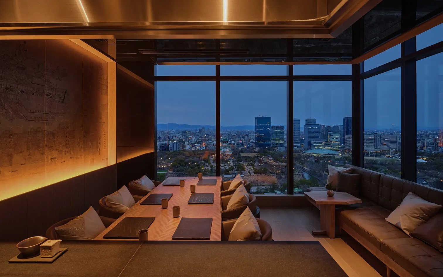 Barin at dusk: a private dining room with low tables, the city lights through the window