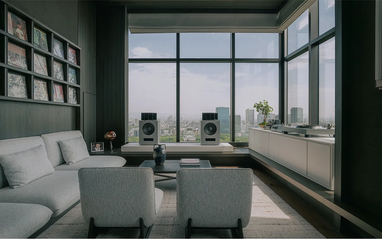 The Listening Room: grey armchairs facing a pair of speakers by the window, the city below