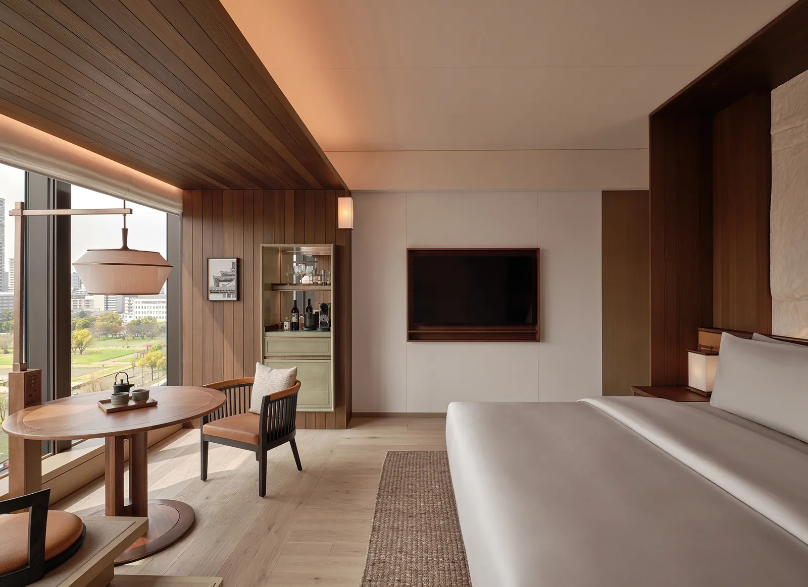 A Deluxe Room: a round table by a window over the park, a television and the end of a king bed