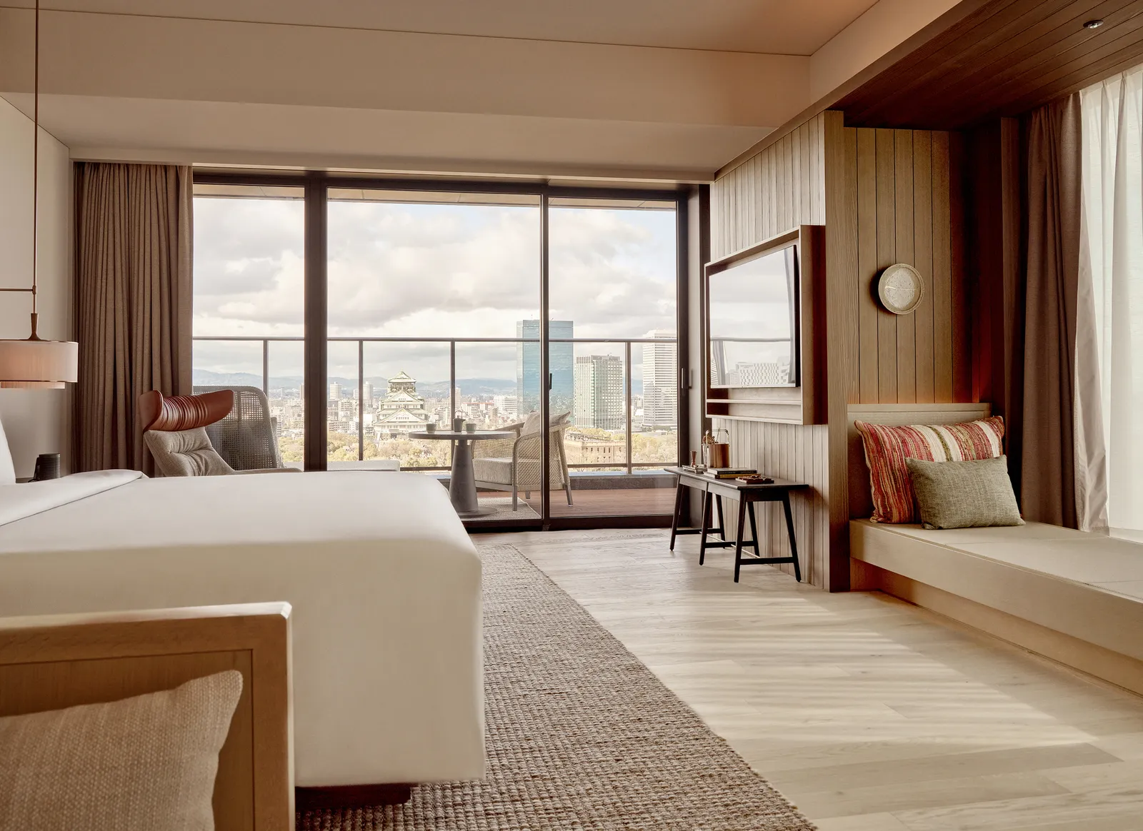 A Junior Suite: the bed, a daybed with cushions and a balcony over the city