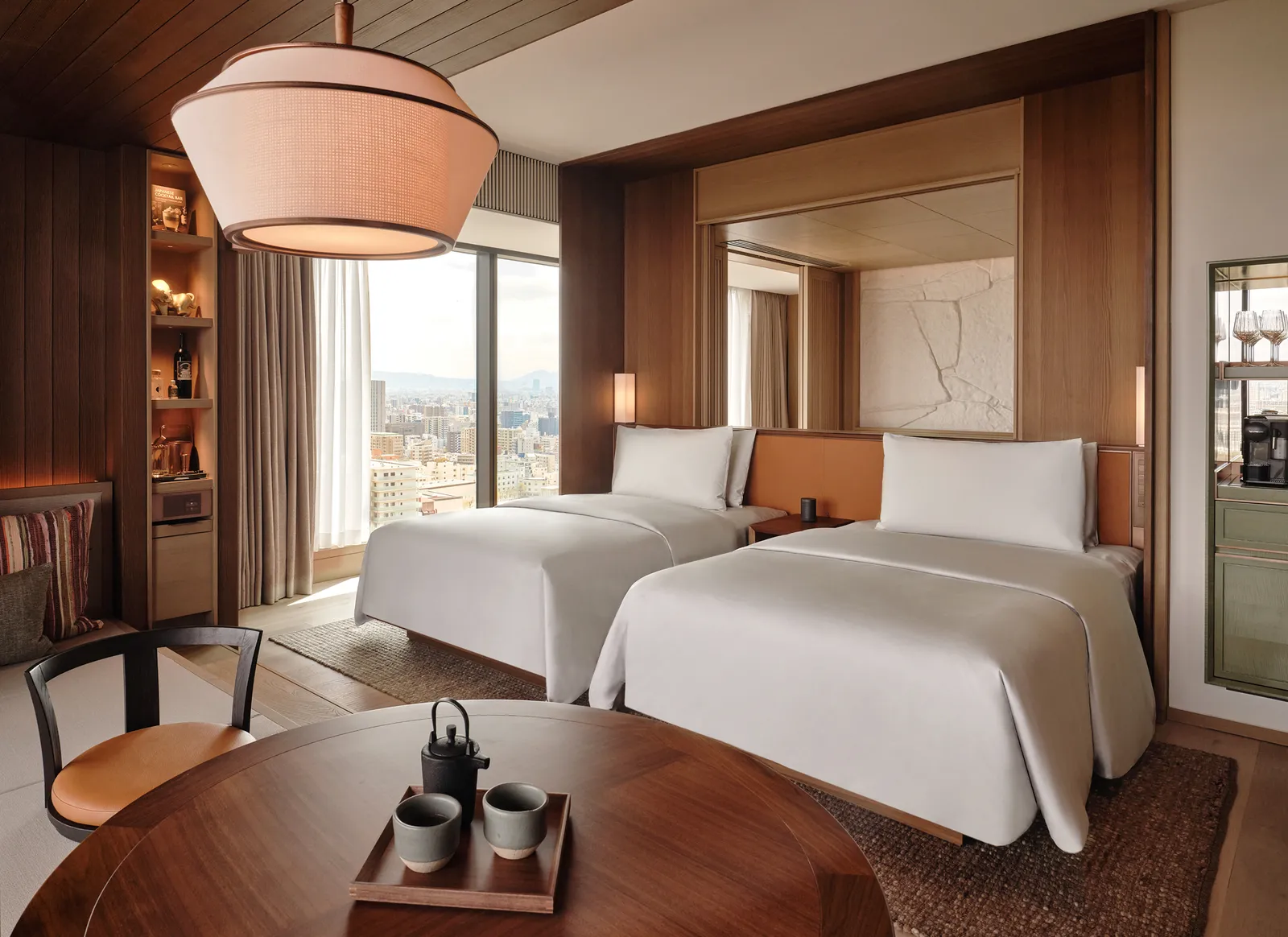 An Urban Suite: 2 beds under a large paper lamp, a tea tray on a round table
