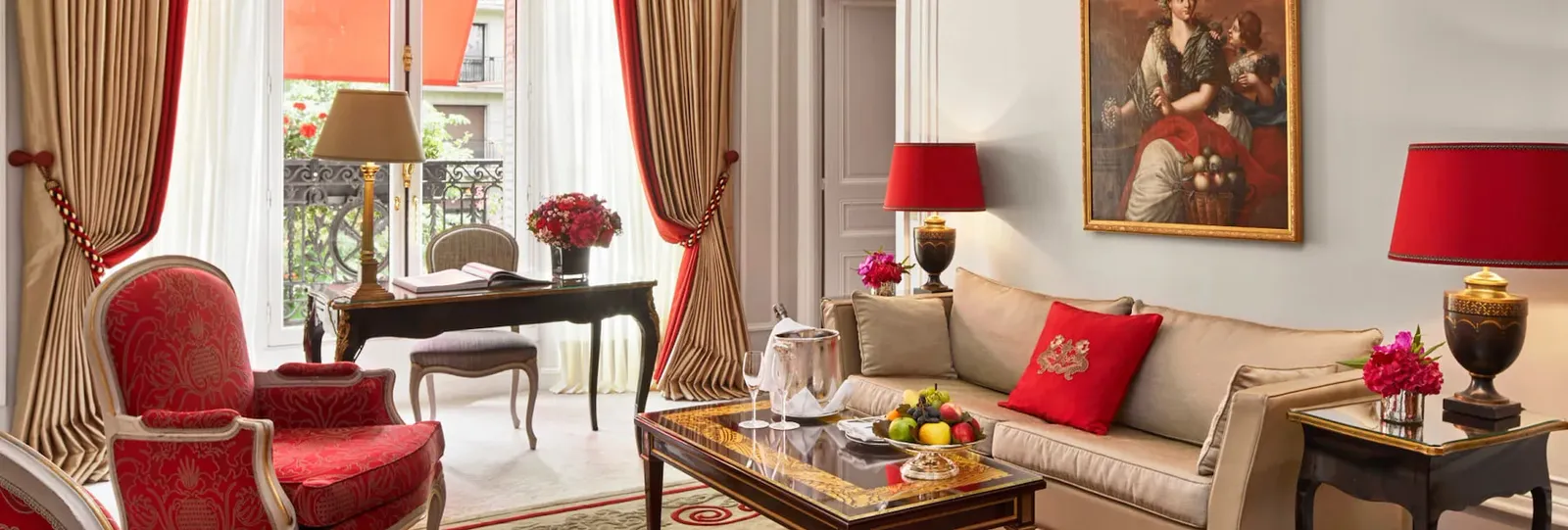 A living room with a pale sofa, red armchair, glass coffee table and painting