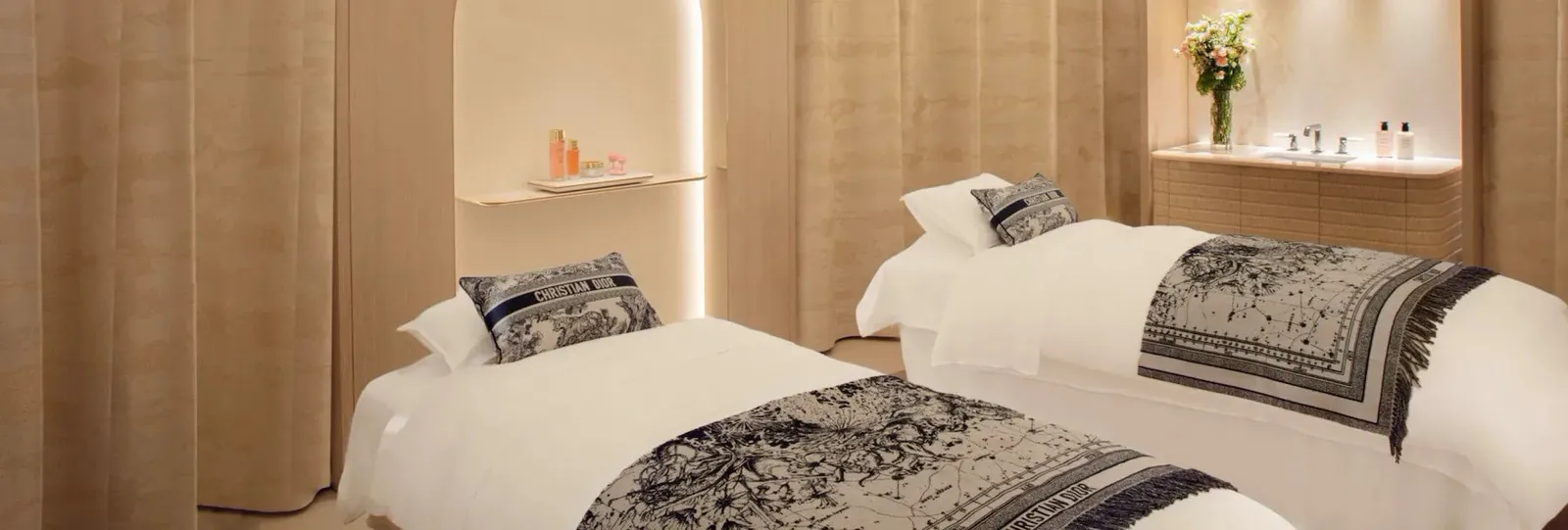 A treatment room with 2 beds, Dior textiles and a basin