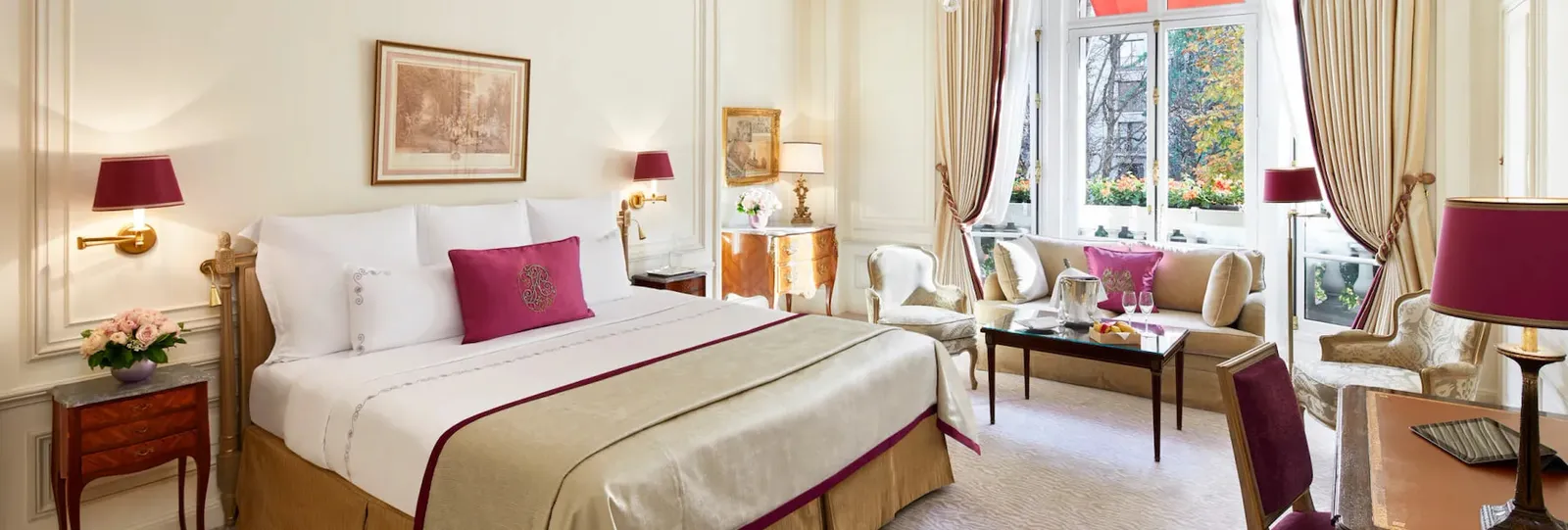 Junior Suite with a bed, red seating and a table near the window