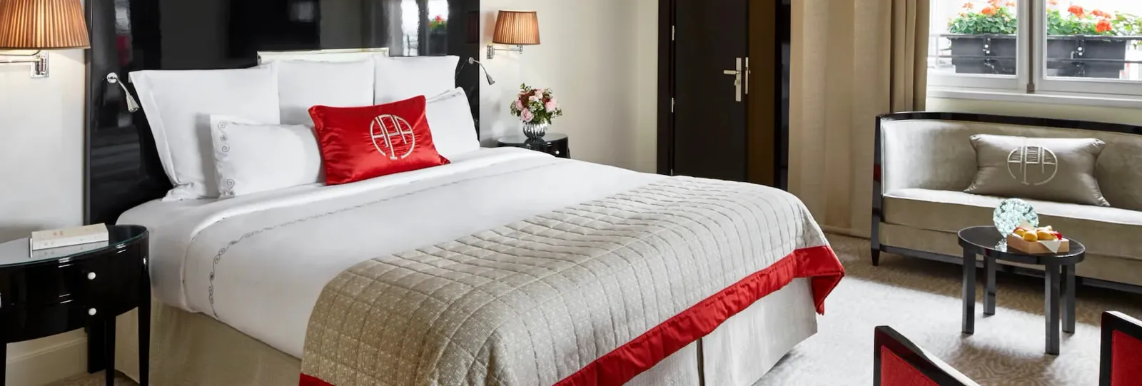 A bedroom with a bed, red cushion, dark panelling and an armchair near the window
