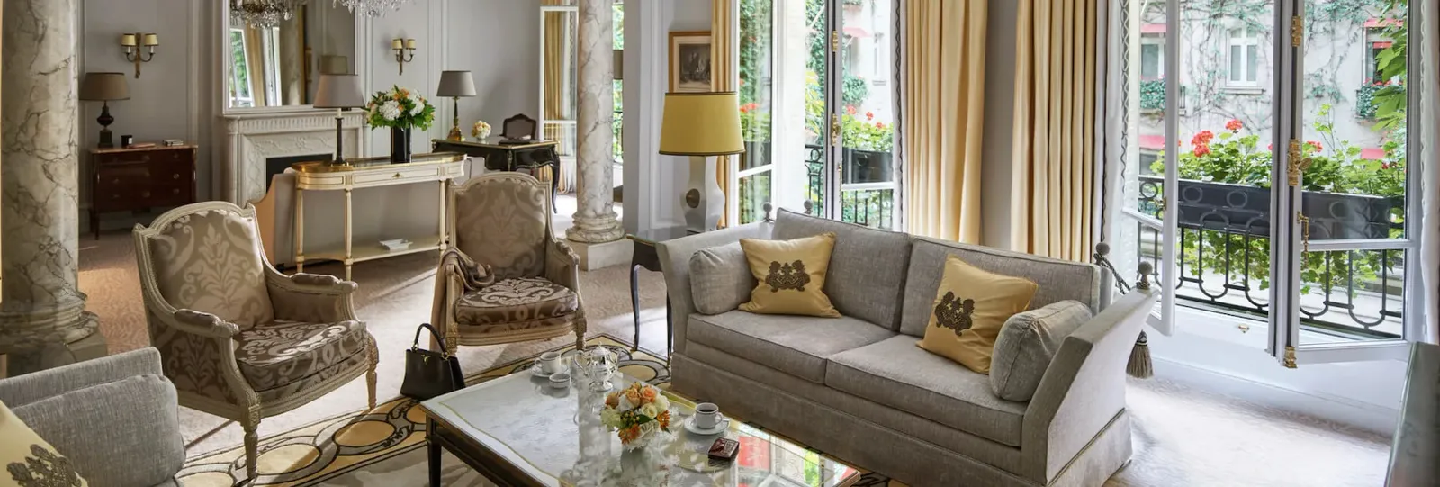 A living room with a pale sofa, armchairs, a large mirror and French doors