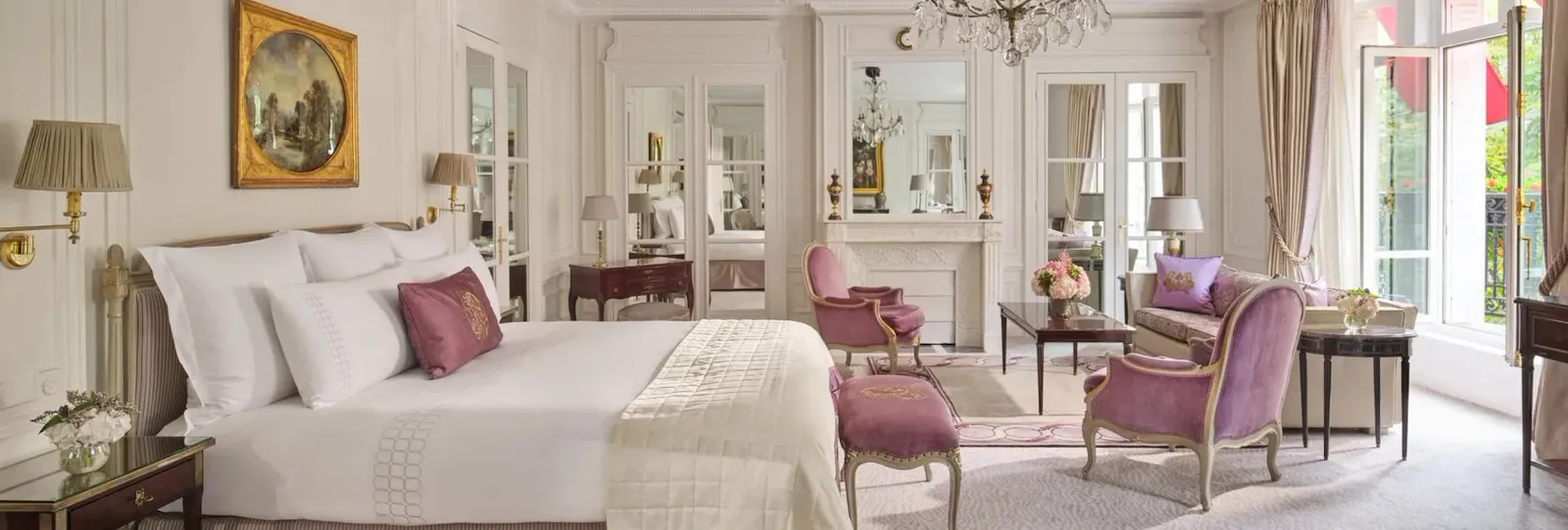A bedroom with a bed, purple seating, a mirror and French doors