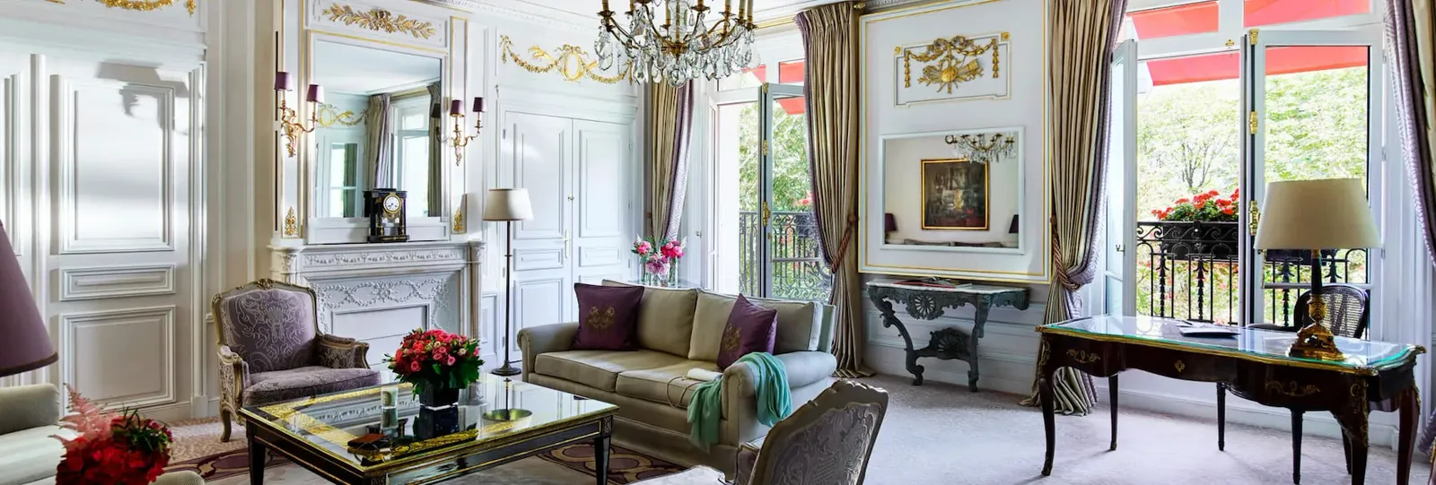 A living room with a pale sofa, purple armchairs, a mirror above the fireplace and chandelier