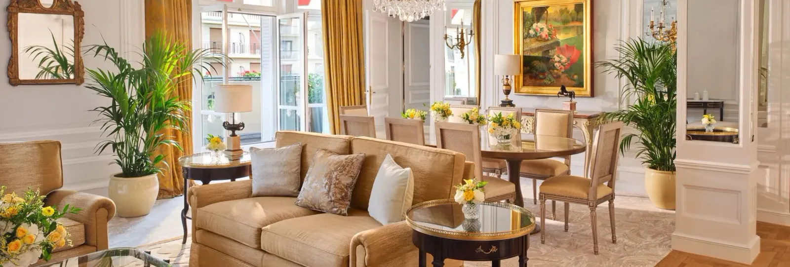 A living room with a sofa, tables and plants, adjoining a dining area