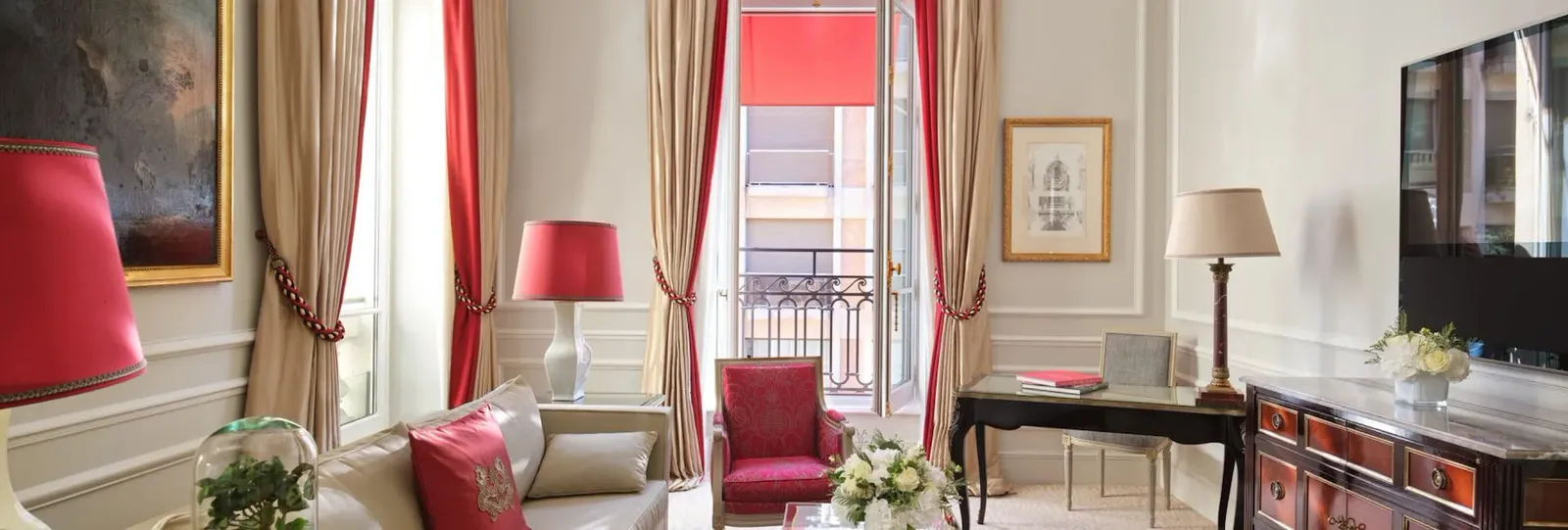 A bedroom with a bed, red lamps, a desk and television