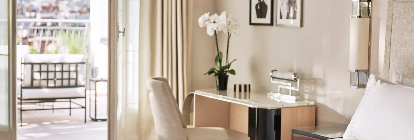 A table and 2 armchairs beside open French doors and an orchid plant