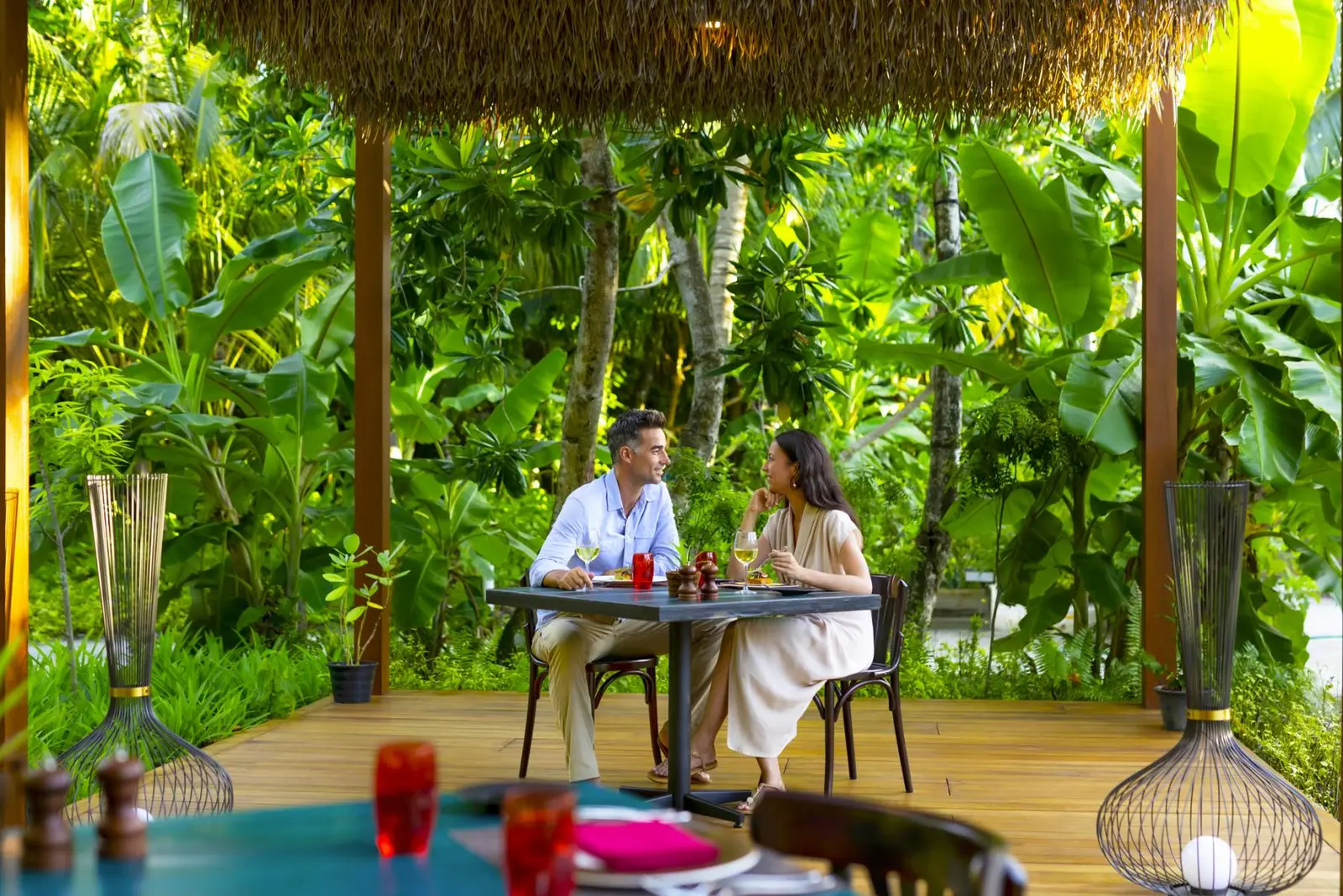 A couple at dinner at Phat Chameleon, among tropical plants under the thatched roof.