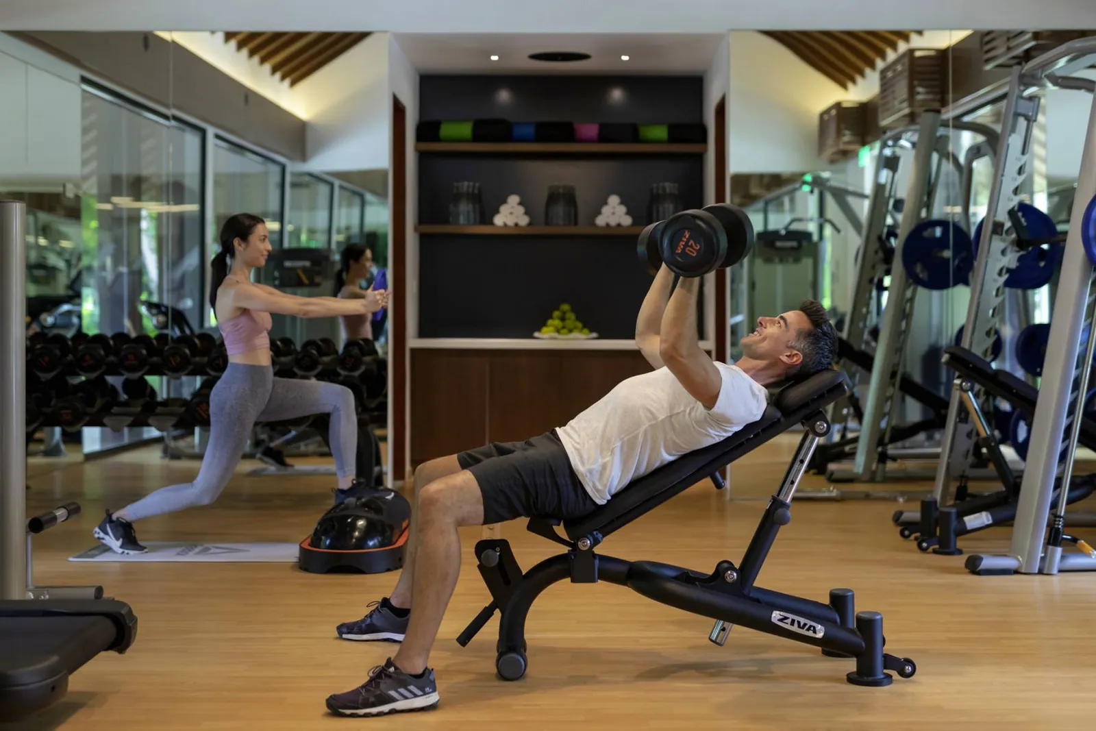 The Pullman Fit gym, 2 guests training among the weights.