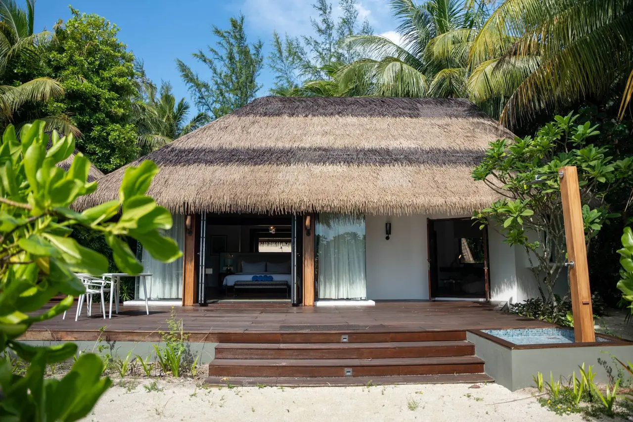 The Family Beach Villa, with its timber veranda and thatched roof among the plants.