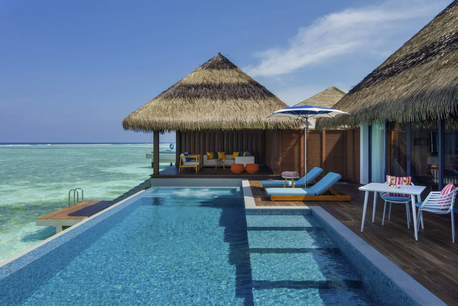 An Ocean Pool Suite’s pool, the deck with loungers and the thatched roof over the water.
