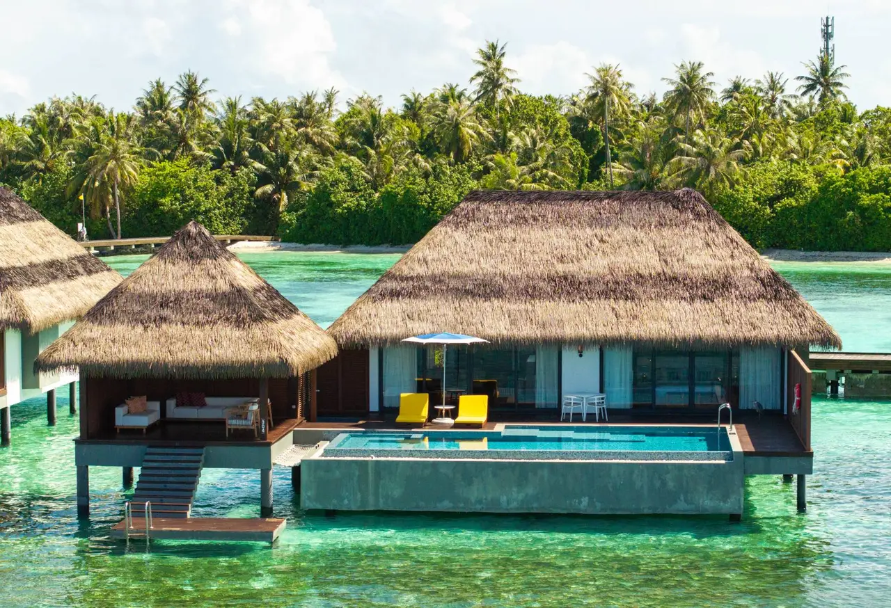 The Two Bedroom Ocean Pool Villa over the water, its long pool in front of the 2 thatched roofs.