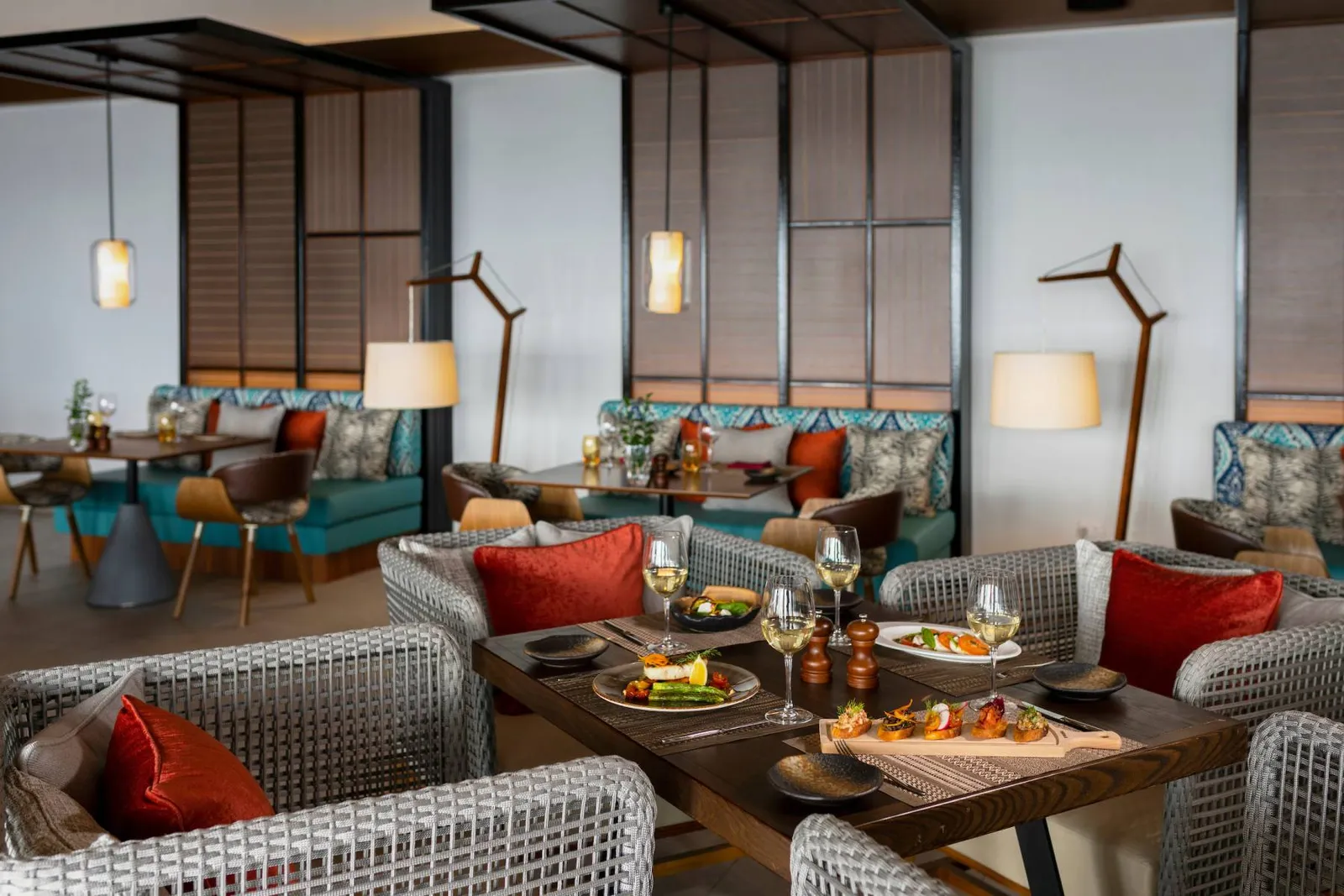 Souq Oven’s dining room over the water, with coloured sofas and laid tables.
