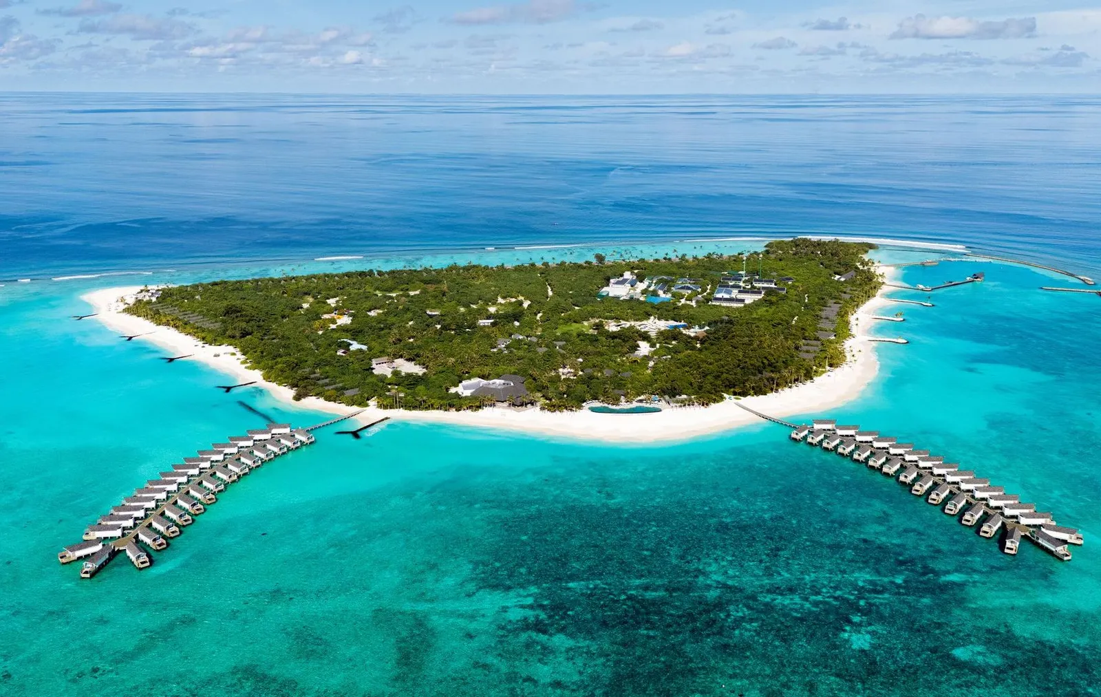 Kudakurathu from above: the green island with its ring of sand and the 2 jetties of water villas on either side.