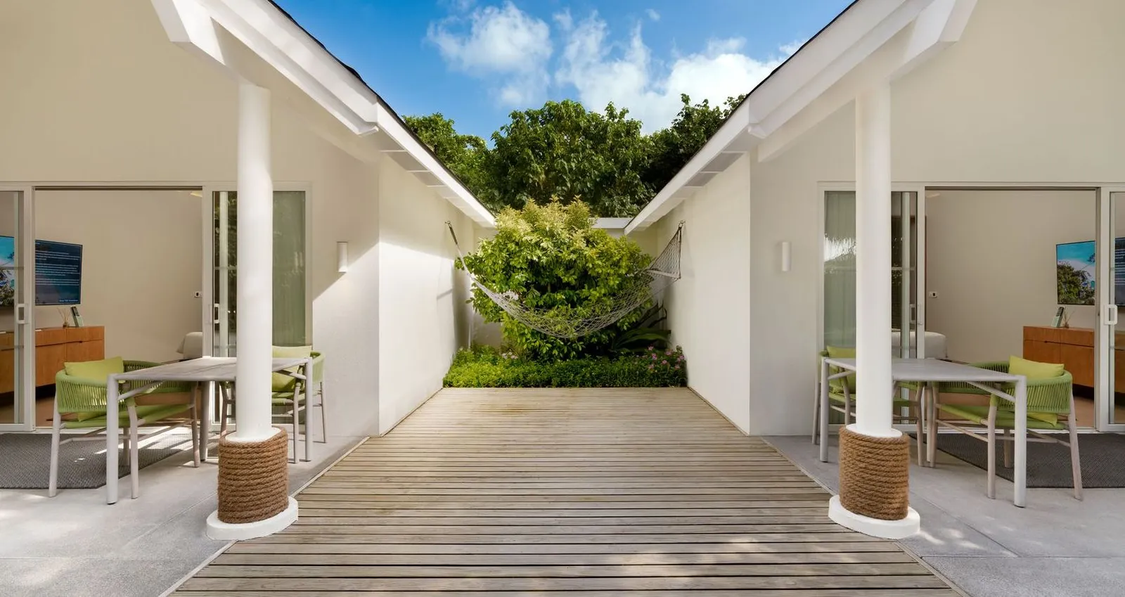 The courtyard between the 2 bedrooms of a 2BR Family Beach Villa, with the hammock, the tables and the timber deck.