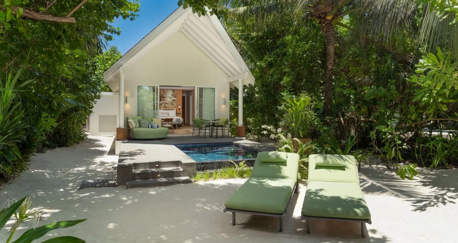 A Beach Villa with Pool: the white villa, the small pool and 2 green loungers on the sand.