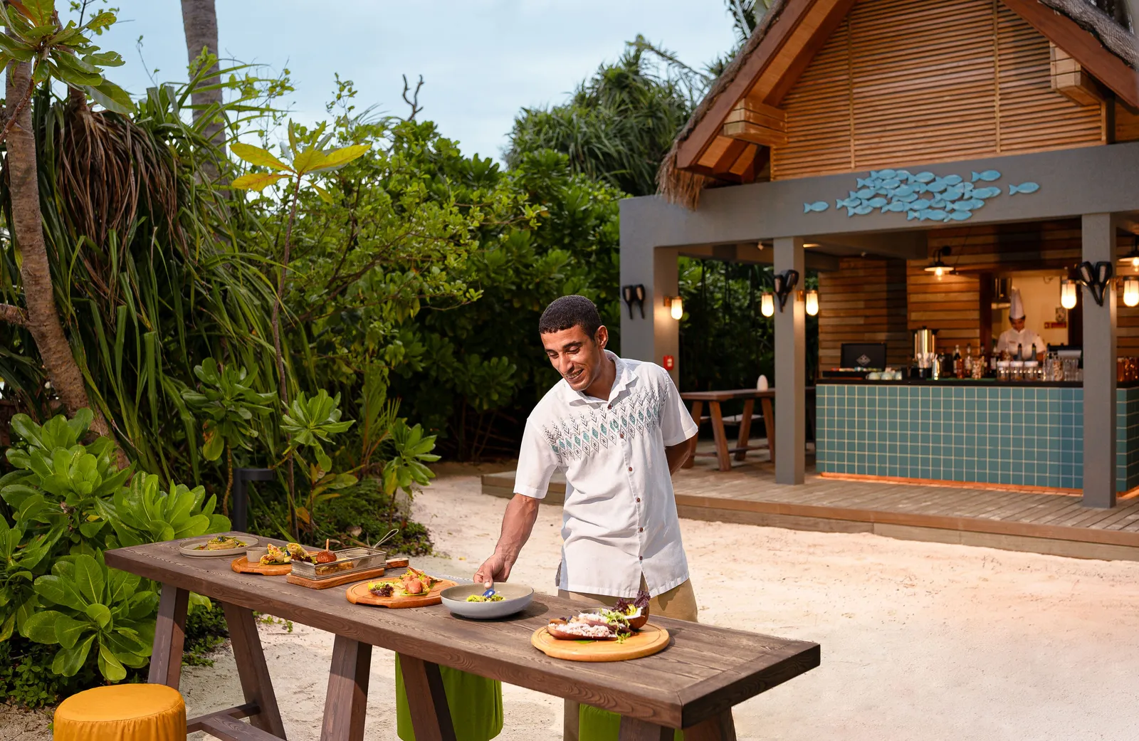 Seb’s Shack, the timber hut on the sand, with a waiter setting plates on an outdoor table.