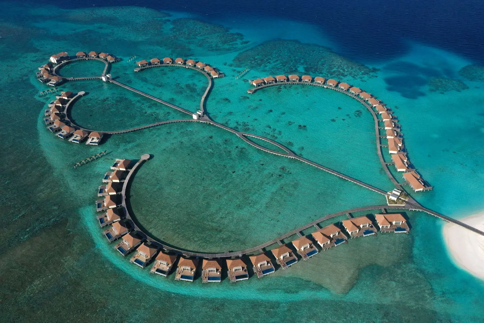 The north wing of overwater villas from above: 2 loops of villas joined by a jetty over the lagoon.