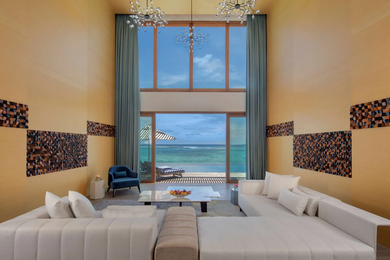 The presidential villa’s double-height living room, white sofas and the glass wall on to the sea.