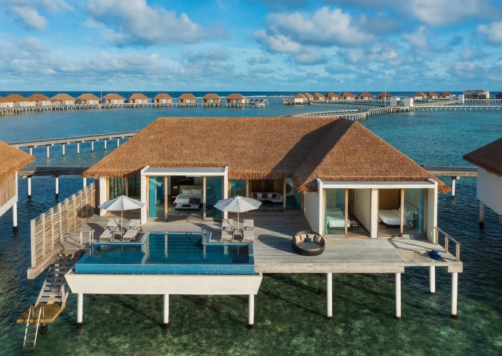 A 3-bedroom overwater villa, its pool at the end of the deck and the other villa jetties behind.
