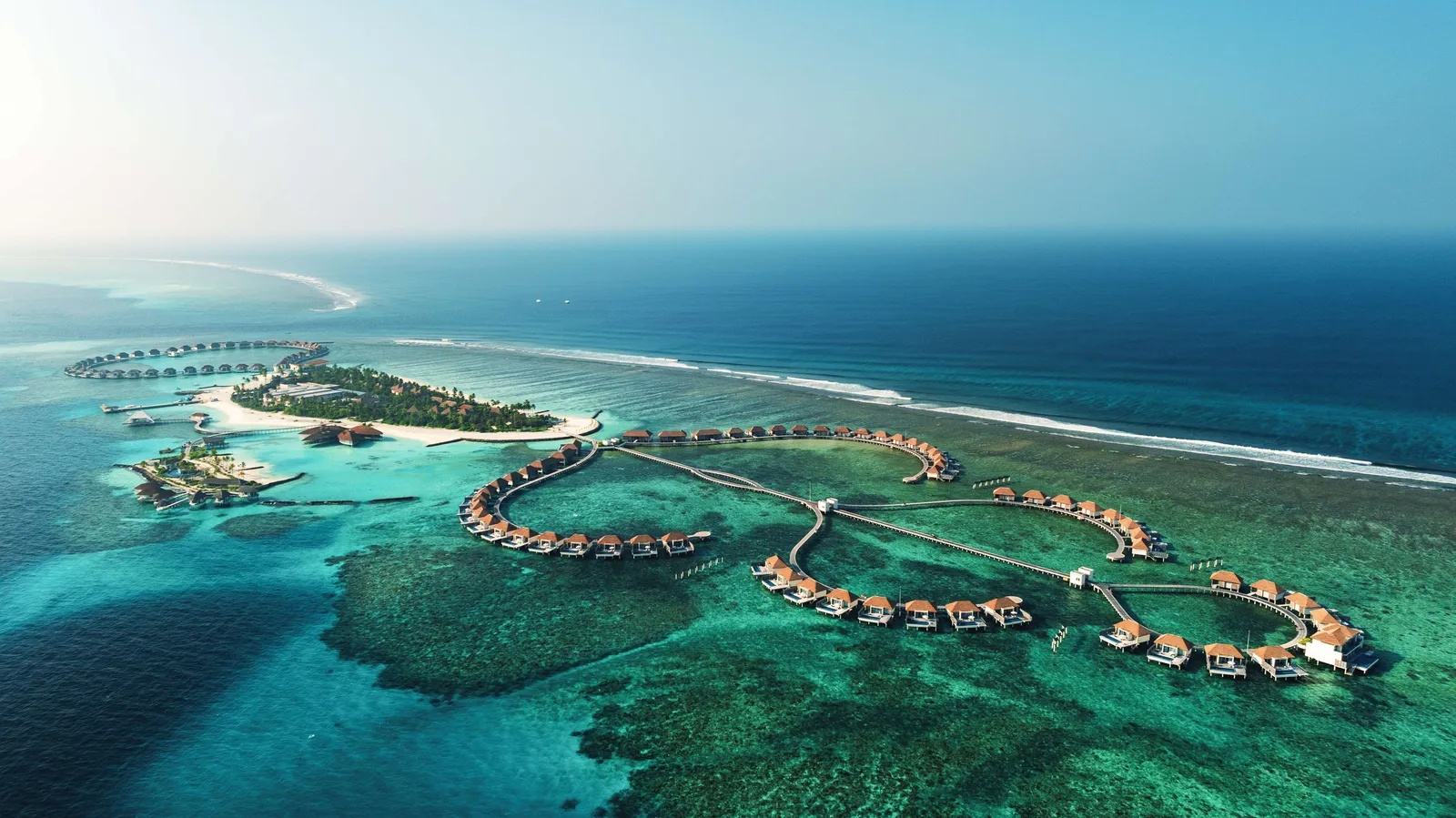 Huruelhi from above, its beach and greenery and the overwater villa jetties out over the reef.