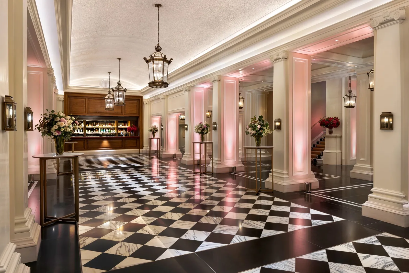 The hotel’s great corridor: a black-and-white chequered floor, columns and pink light on the walls