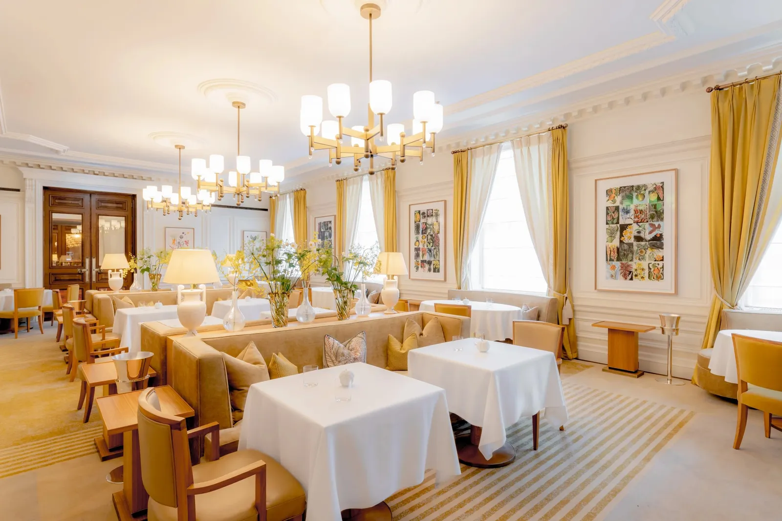 Mauro Colagreco’s dining room: white tables, velvet chairs and chandeliers, with tall windows