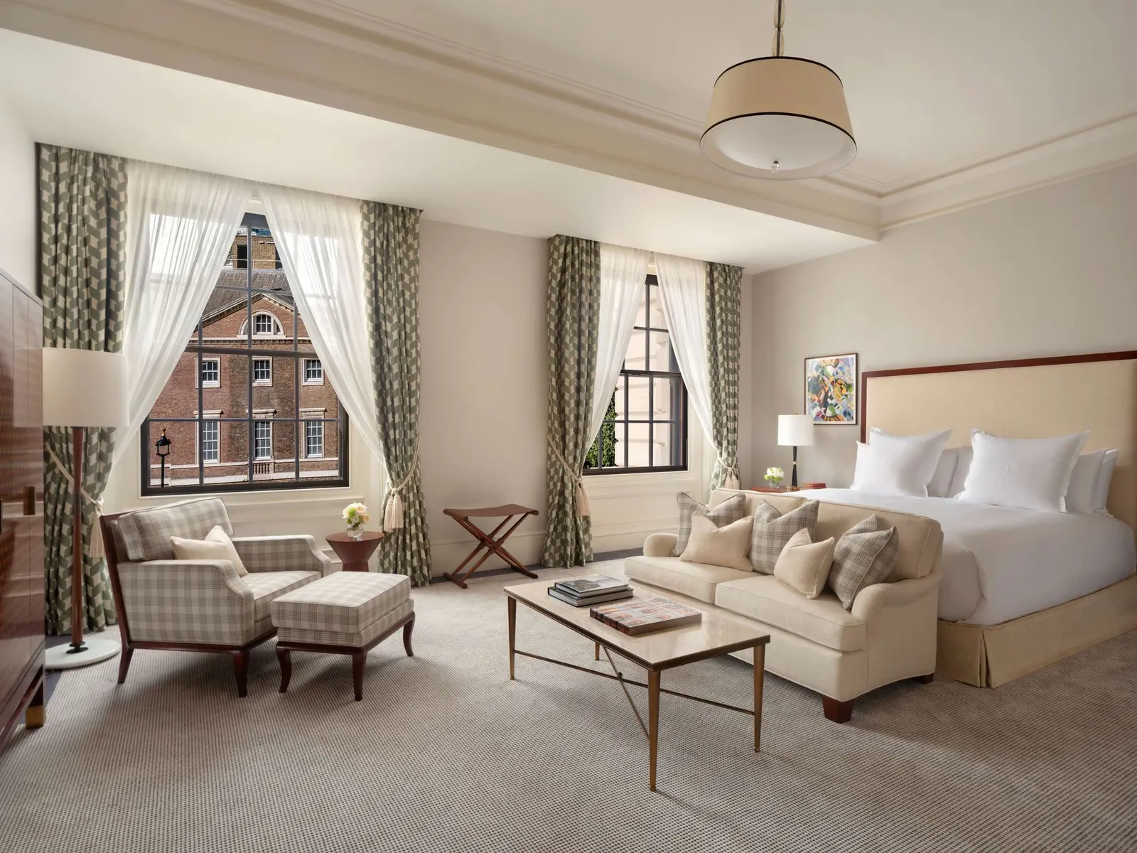 A Junior Suite: a white bed, armchairs and a low table in one large bright room