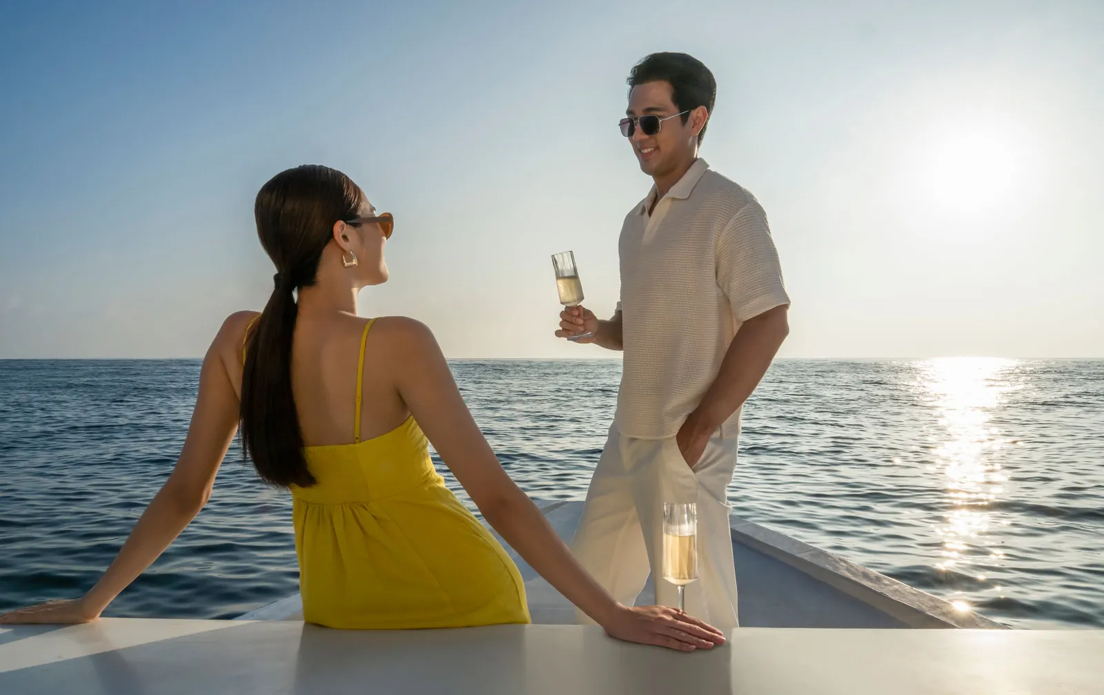 A couple at the bow at sunset, glass in hand, on the dolphin cruise
