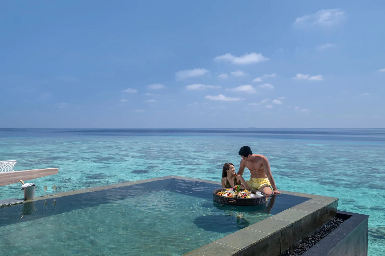 A floating breakfast in an overwater villa’s pool, the lagoon beyond its edge