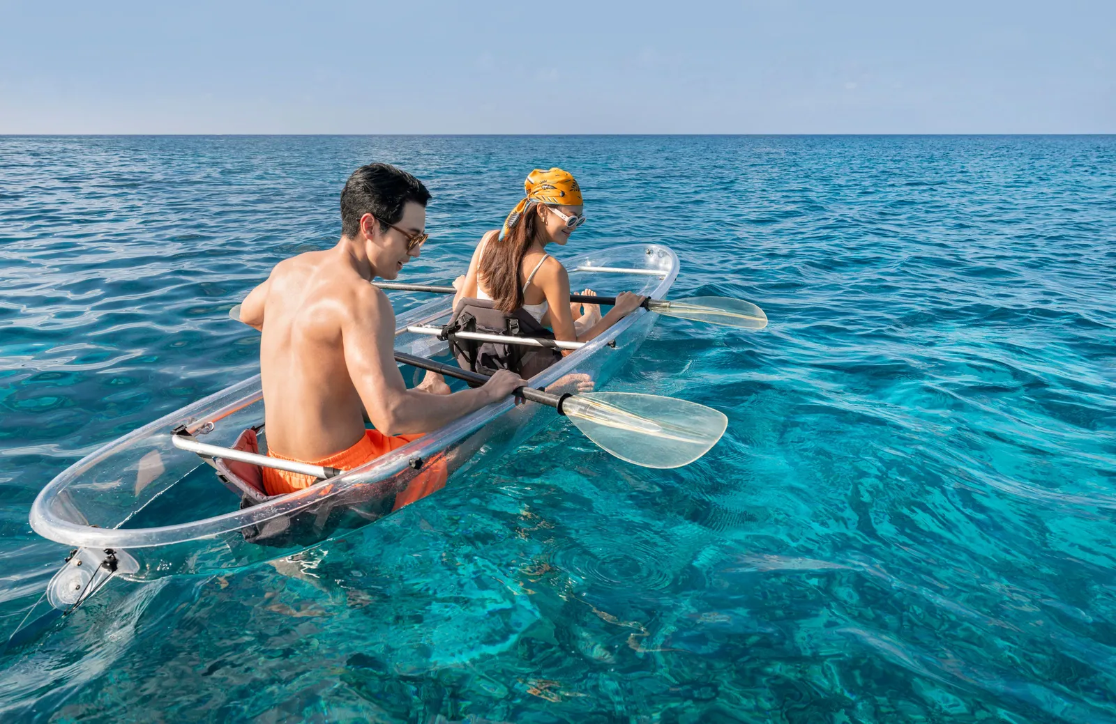 2 people in a clear kayak over the turquoise water of the reef