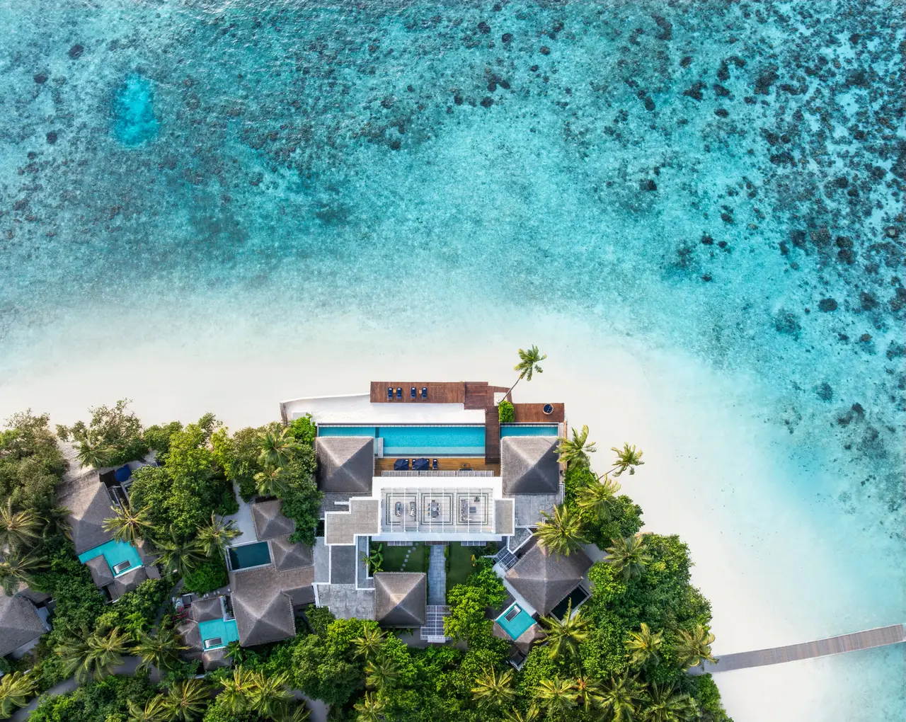 The Halcyon Grand Estate from above, the white villa between the palms and the beach