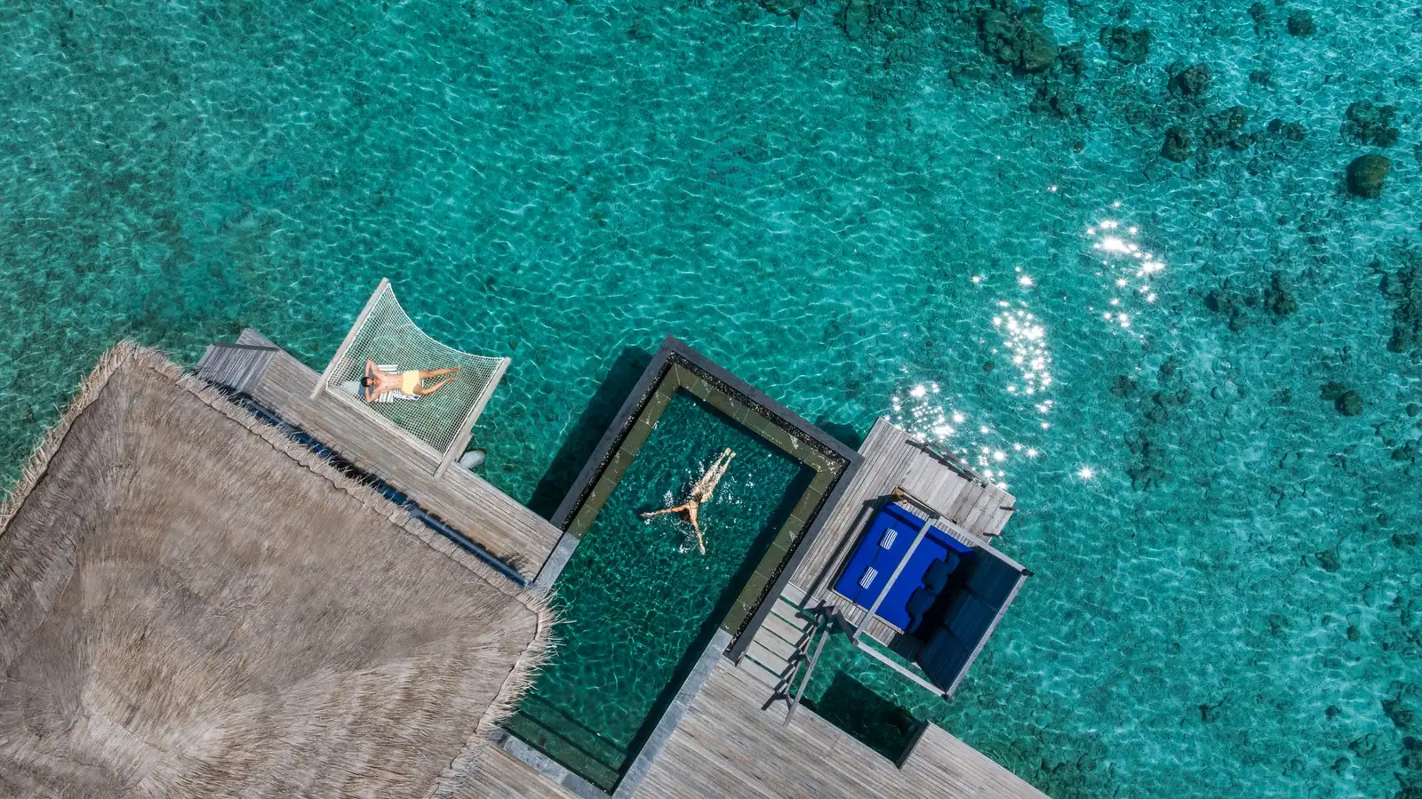 An overwater villa from above: the pool, the hammock net and the deck over the lagoon