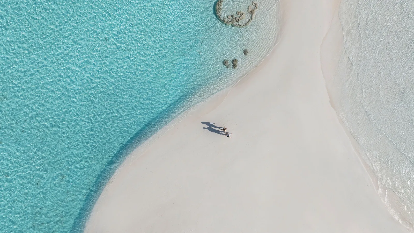 A white sandbank in the lagoon from above, a picnic set under a parasol