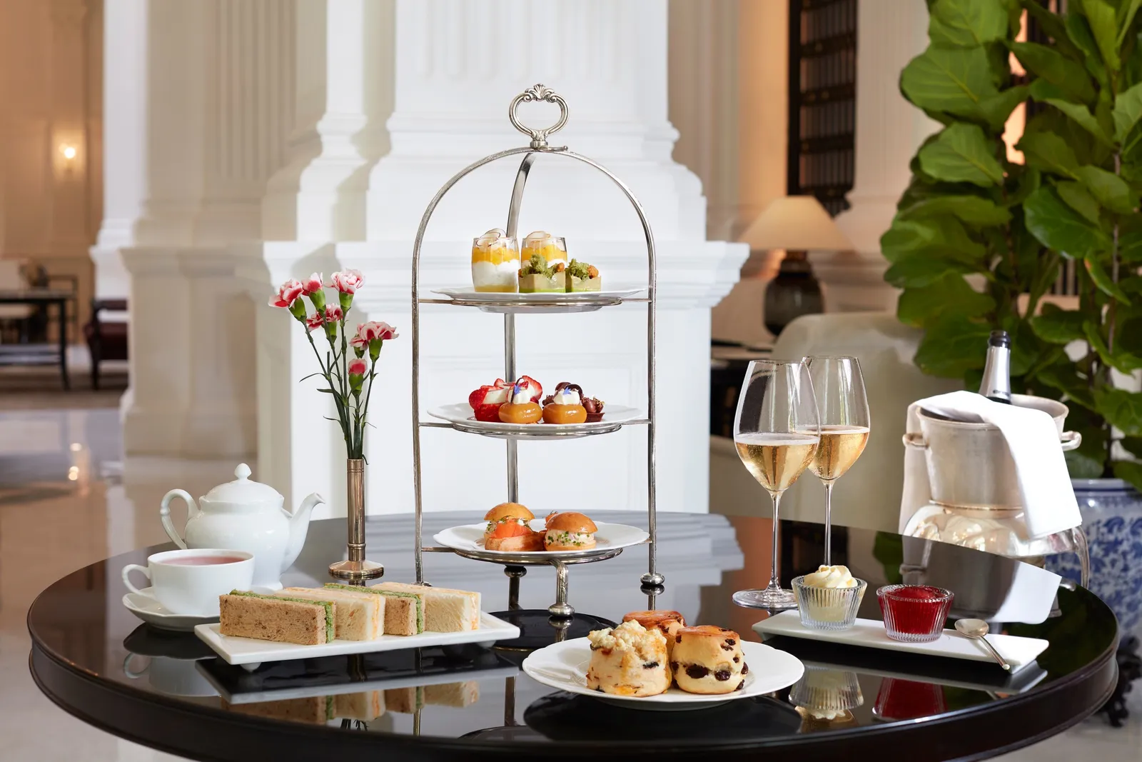 Afternoon tea in The Grand Lobby: the 3-tier silver stand, a teapot, 2 glasses of Champagne and the white columns.