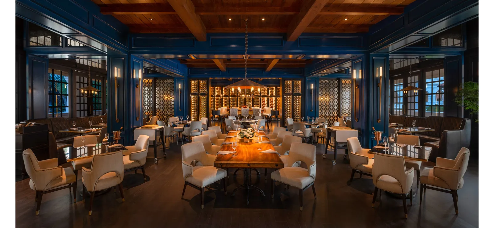 The dining room of Butcher’s Block: dark-blue walls, pale armchairs and a long timber table at the centre.