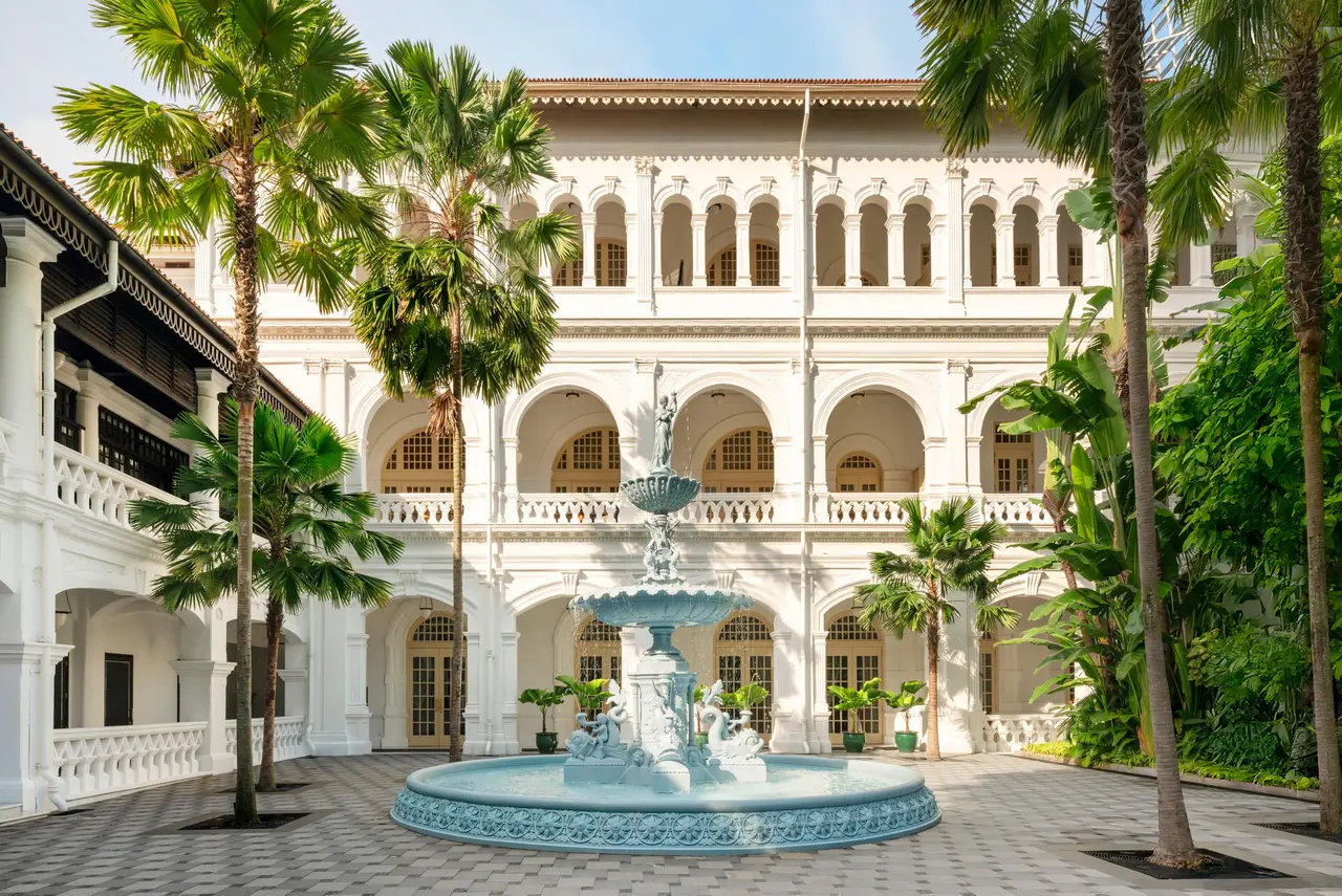 An inner courtyard with the pale-blue cast-iron fountain, palms and 3 floors of white loggias.