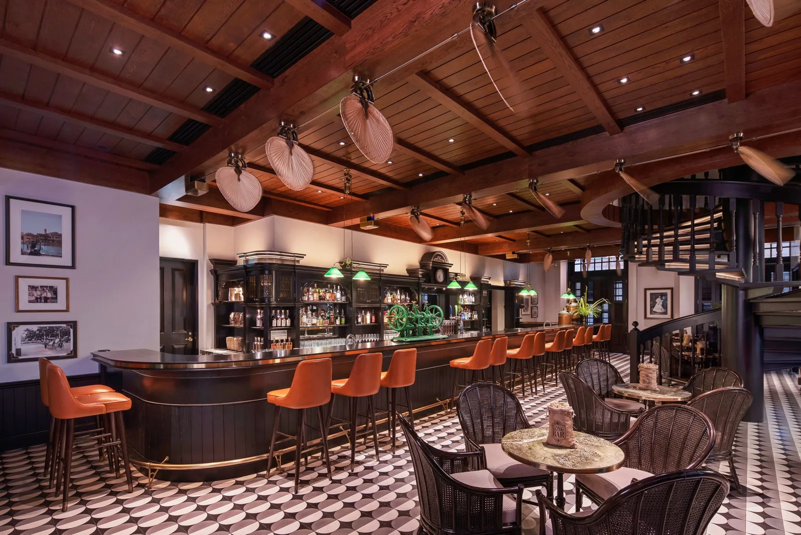 The Long Bar: the curved counter with orange stools, the timber ceiling with its palm-leaf fans and the chequered floor.