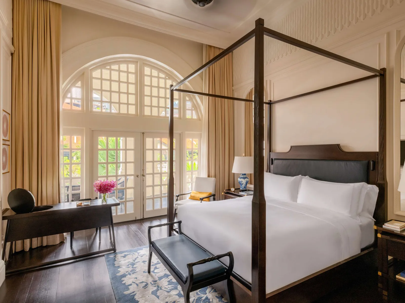 A Grand Hotel Suite bedroom: the four-poster bed in front of the tall arched window, with the writing desk.
