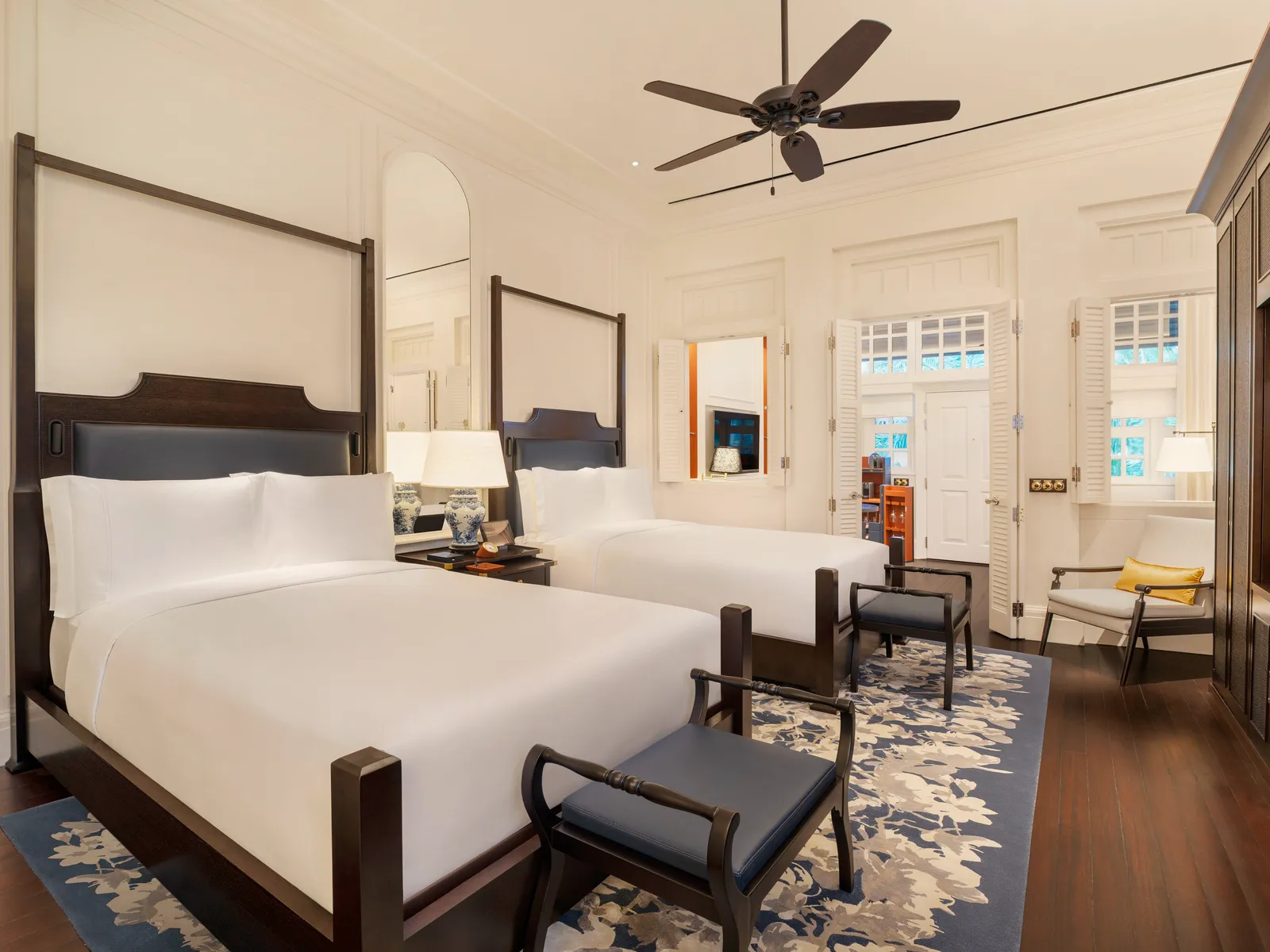 A Personality Suite bedroom with 2 double beds and the flowered rug on dark floorboards.